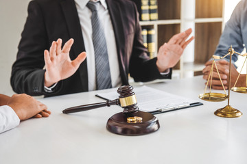 man with hands raised defensively with gavel and divorcing couple