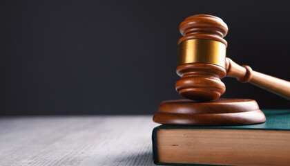 A wooden judge’s gavel rests on a block atop a closed book, symbolizing how postnuptial agreements become enforceable in the eyes of the law, set against a dark background and a light wooden surface.