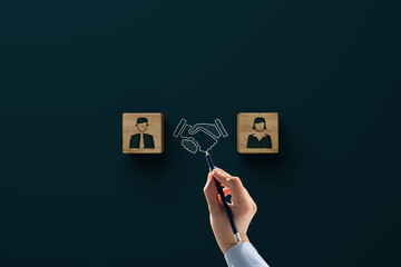 A hand draws a handshake between two wooden blocks, each displaying a male and female businessperson icon, symbolizing agreement or partnership—reflecting what to expect in divorce mediation—against a dark background.
