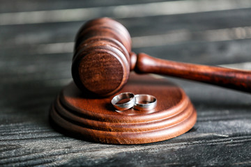 A wooden judge’s gavel rests on a sound block, with two silver wedding rings placed beside it—symbolizing divorce or legal separation and hinting at how to get a fast divorce.