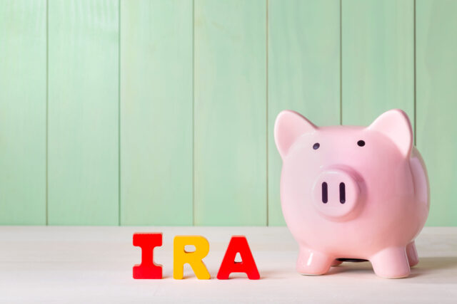 A pink piggy bank sits on a light surface with colorful letters spelling