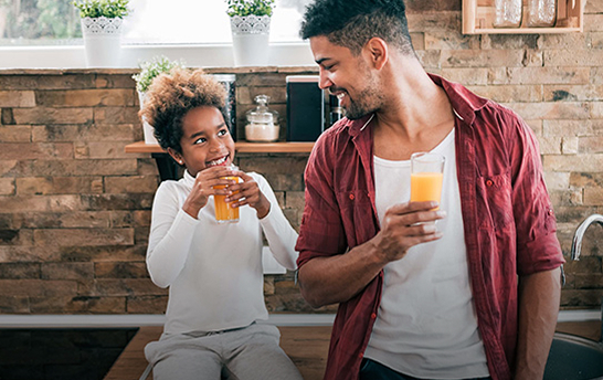 father drinking orange juice with his child