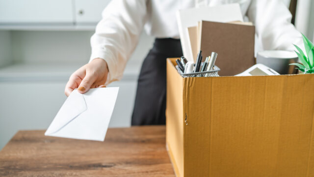 Business woman sending resignation letter and packing Stuff Resign Depress or carrying business cardboard box by desk in office. Change of job or fired from company.